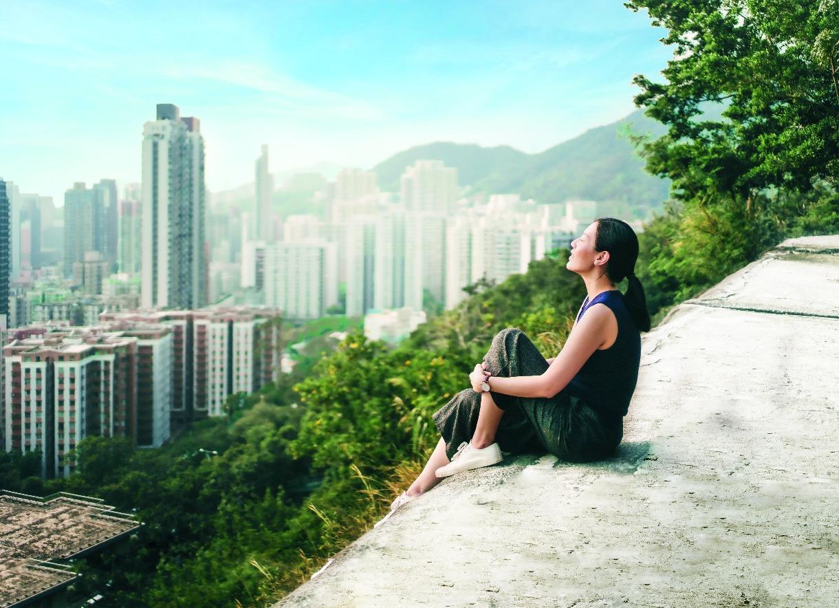 Young woman with eyes closed enjoying the tranquility and the spectacular city skyline